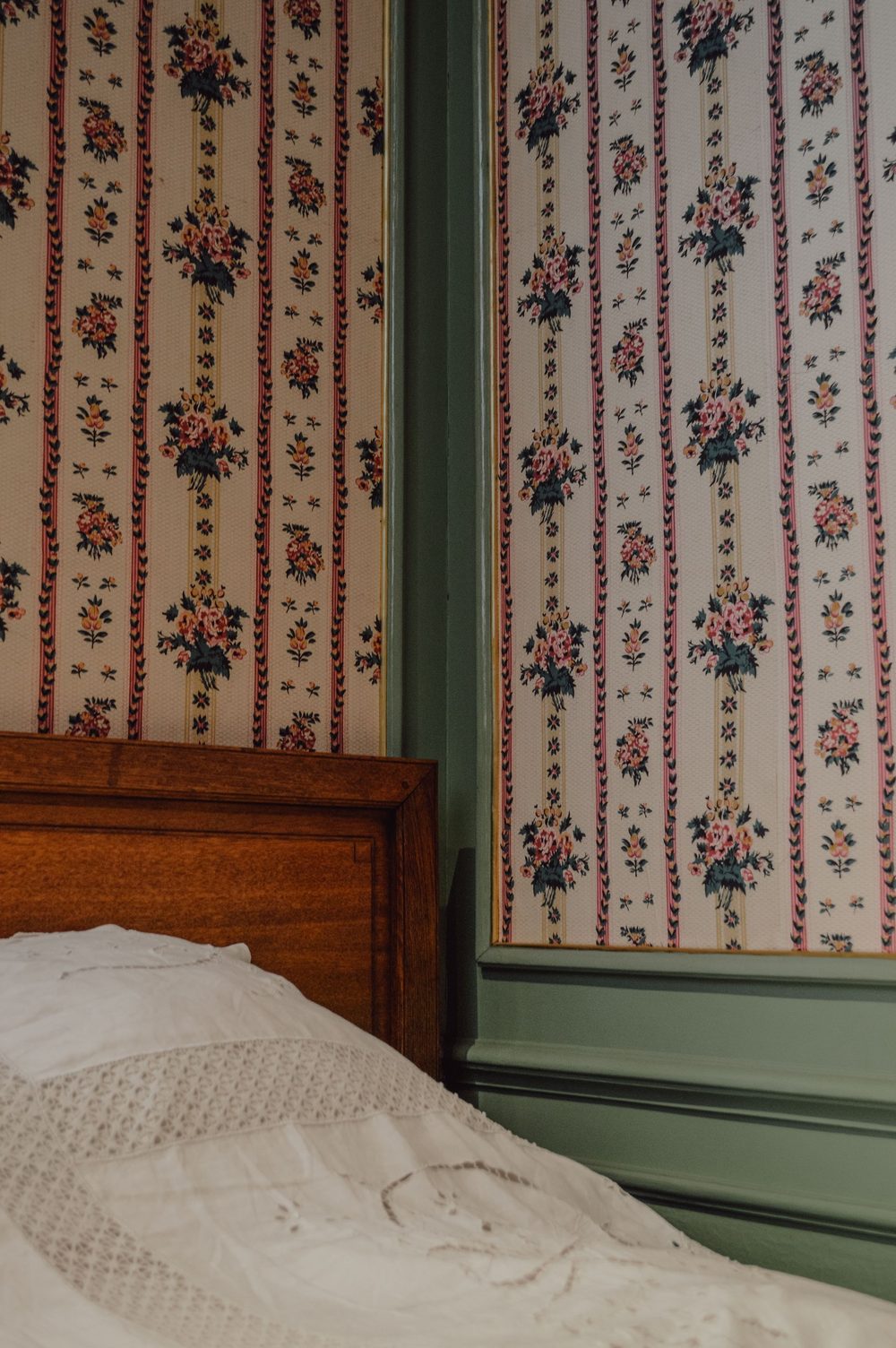 Classic floral-stripe wallpaper beside a carved wooden cabinet