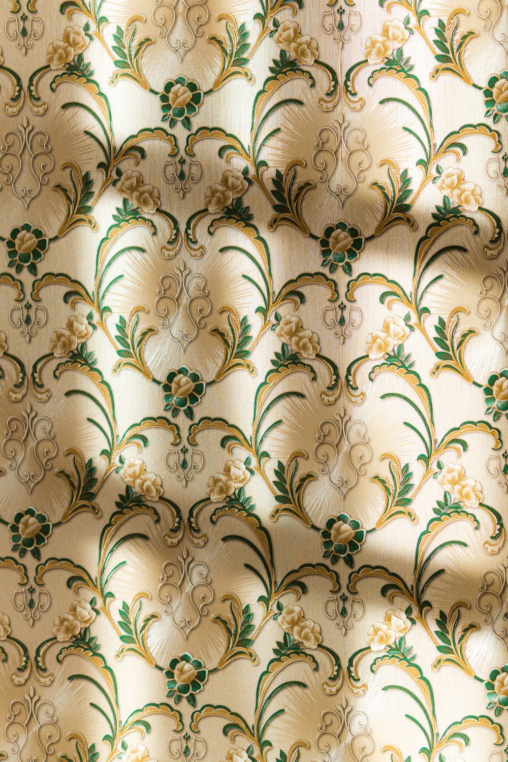 Detail of a cream and gold damask wallpaper with green foliage