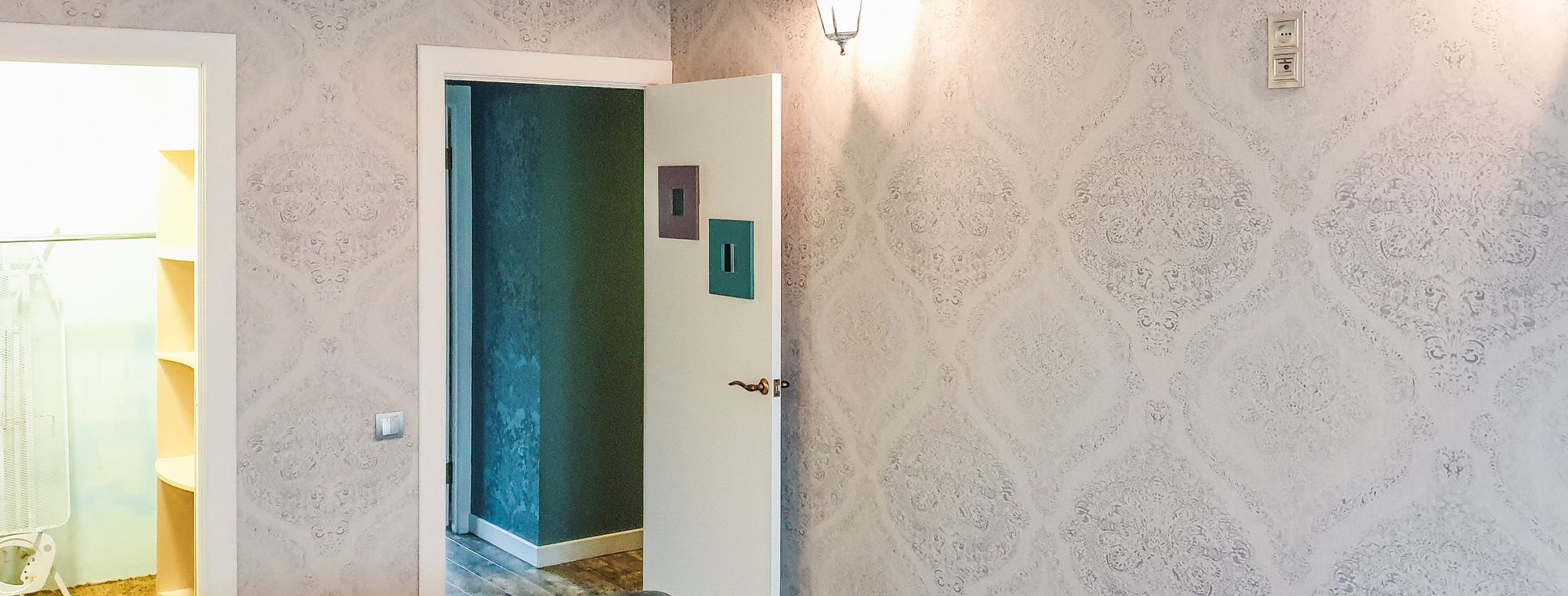 A neutral residential room finished with a subtle grey damask wallpaper